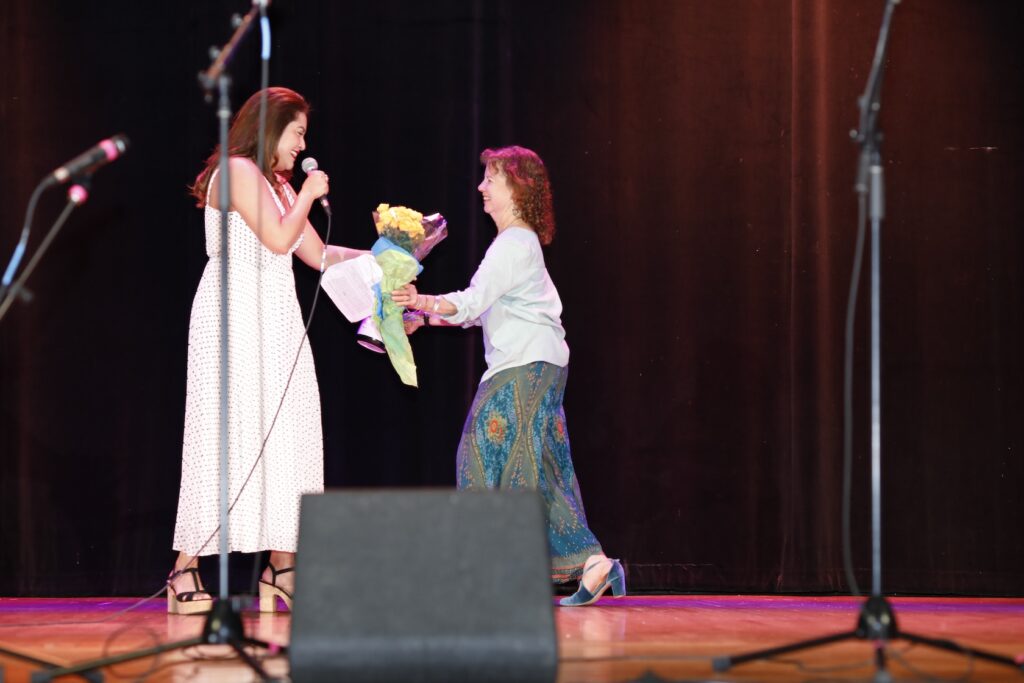 CNA Director Laurie handing MC Biani flowers